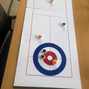 Auf dem Bild ist das Tischspiel Curling auf einem Tisch zu sehen.